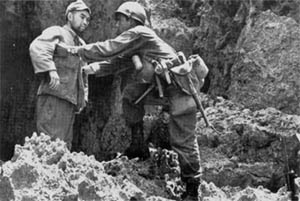 A U.S. soldier searches a surrendering Japanese soldier.