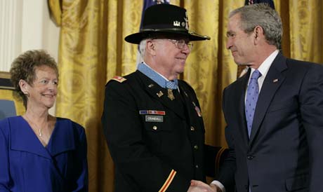 Crandall with the Medal of Honor shakes hands with President George Bush as his wife, Arlene looks on in the East Room of the White House, Monday, Feb. 26, 2007.