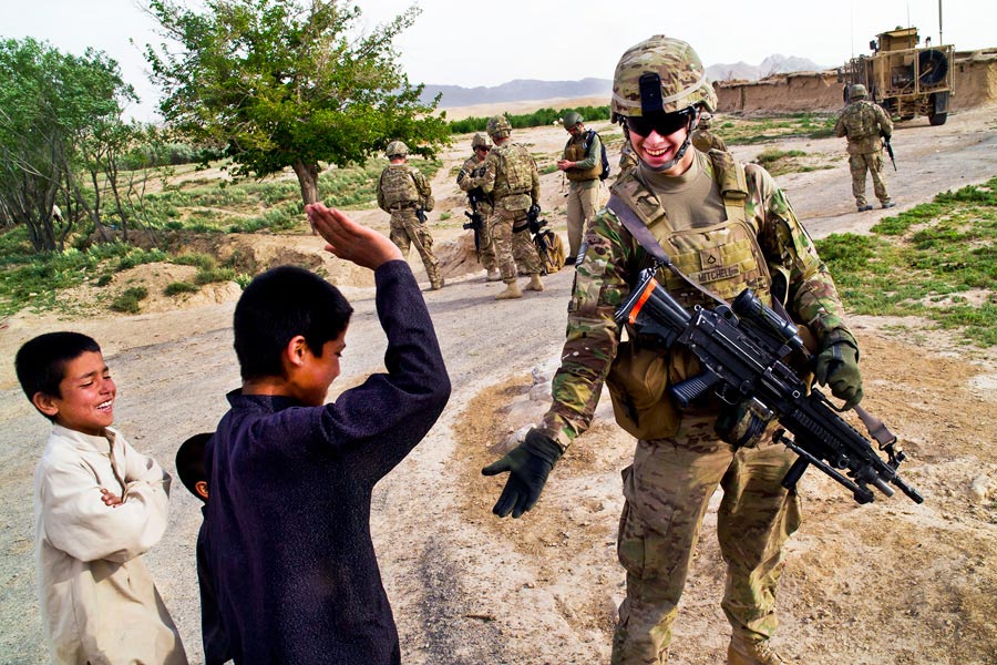 Private Richard Mitchell, Provincial Reconstruction Team Zabul, visits with children of a village in Afghanistan