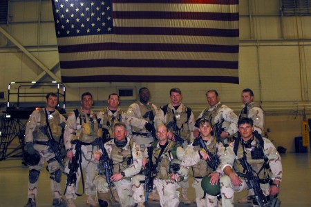 Soldiers standing front of a large American flag