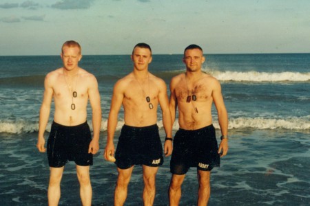 Three Soldiers staning in the ocean with their swimssuits and dog tags on