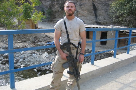 Bearded Staff Sergeant Robert Miller standing on a bridge