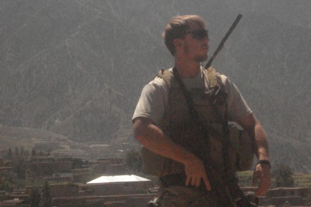 Staff Sergeant Robert Miller wearing sunglasses and holding a gun