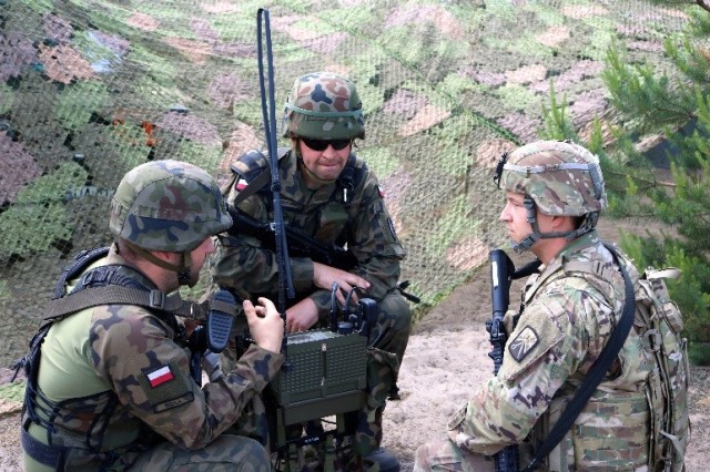 TORUN, Poland -- Sgt. Joshua Elkins (right), a nodal network systems operator assigned to the 504th Brigade Signal Company, 16th Special Troops Battalion learns how to use a Polish radio June 8. (Photo by 1st Lt. Hilary Klotz, 16th Sustainment Bde. Public Affairs)