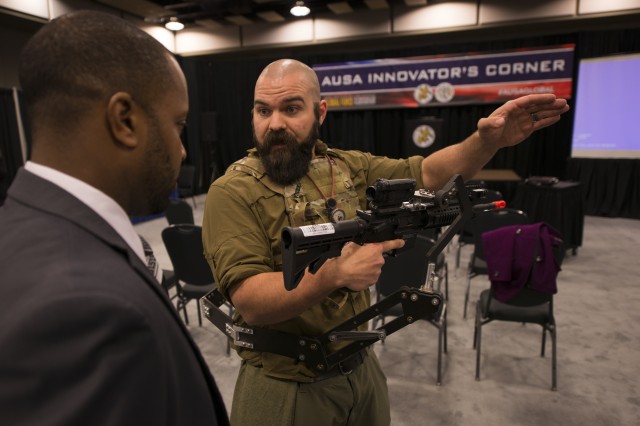 Zac Wingard, a mechanical engineer at the Army Research Laboratory, explains the "third arm" body-worn weapon mount during the Association of the United States Army's Global Force Symposium in Huntsville, Ala., March 14, 2017. The lab is developing the device that could lessen Soldier burden and increase lethality. Weighing less than 4 pounds, the device attaches to a Soldier's protective vest and holds their weapon, putting less weight on their arms and freeing up their hands to do other tasks.