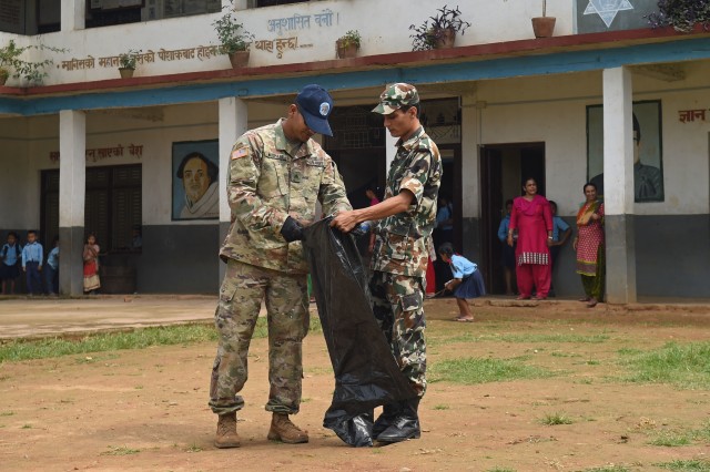 U.S. Army Sgt. Rajeev Neupane, 523rd Engineer Support Company, 130th Engineer Brigade interior electrician, and a Nepal army counterpart pick up debris near an engineering site at the Shree Mahendra Higher Secondary School during Pacific Angel (PACANGEL) 17-4 in Gorkha, Nepal, Aug. 18, 2017. PACANGEL is a multi-lateral humanitarian assistance civil military engagement, which improves military-to-military partnerships in the Pacific while also providing medical health outreach, civic engineering projects and subject matter exchanges among partner forces. (U.S. Air Force photo by Airman 1st Class Valerie Monroy)