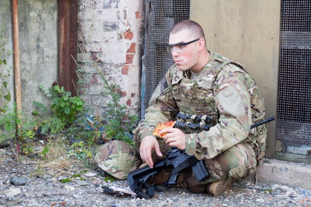 A Soldier enjoys a Meal, Ready-to-Eat pizza developed by scientists in the Combat Feeding Directorate at the Natick Soldier Research, Development and Engineering Center. CFD used a combination of technologies involving water activity, pH levels, and innovative packaging to create a shelf-stable pizza.