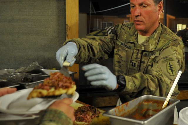 Capt. Rinaldo Manago, Base Defense Operations Center commander, hands a freshly made pizza to a Soldier at Bagram Air Field, Afghanistan, May 29, 2011. Army scientists at Natick Soldier Systems Center recently developed a pizza MRE that will go to full-scale production March 2018.