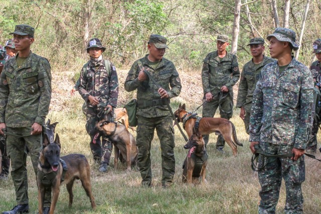 Filipino military members are taught a U.S. method of firearm desensitization training with their dogs on March 6, 2019 at Camp Aquino. They wait for the gunfire to observe their dogs reaction to the noise. Salaknib is an annual, bilateral exercise sponsored by U.S. Army Pacific and hosted by the Philippine Army, contributing to and enhancing U.S. and Philippine defense readiness and tactical interoperability while strengthening multinational relationships.