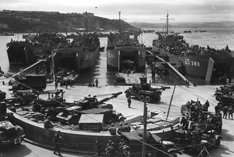 Artillery equipment is loaded aboard landing craft.