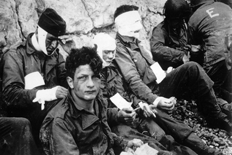 Soldiers wounded while storming Omaha Beach wait for evacuation to a field hospital.
