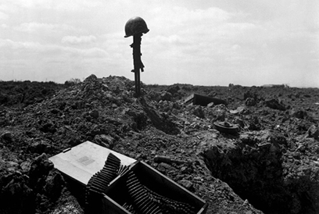 Fellow Soldiers erect monument for the fallen. Helmet resting on rifle spiked into ground.