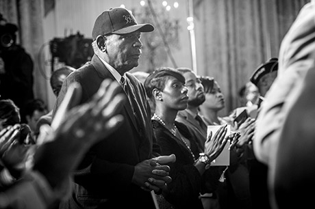 A former Soldier assigned to the 369th Infantry Regiment "Harlem Hellfighters," proudly wears the regiment's name on a ball cap while President Barack Obama bestows the Medal of Honor to Sgt. Henry Johnson, a World War I, 369th Soldier, at the White House, June 2, 2015. Then-Pvt. Johnson, an African-American, distinguished himself as a member of 369th Infantry Regiment "Harlem Hellfighters," 93rd Division, American Expeditionary Forces, during combat operations against the enemy on the front lines of the Western Front in France during World War I. While on night sentry duty, May 15, 1918, Johnson and a fellow Soldier, Pvt. Needham Roberts, received a surprise attack by a German raiding party consisting of at least 12 soldiers. While under intense enemy fire and despite receiving significant wounds, Johnson mounted a brave retaliation resulting in several enemy casualties. When his fellow Soldier was badly wounded, Johnson prevented him from being taken prisoner by German forces. Wielding only a knife and being seriously wounded, Johnson continued fighting, took his Bolo knife and stabbed it through an enemy soldier's head. Displaying great courage, Johnson held back the enemy force until they retreated. The "Harlem Hellfighters" were the first all-black regiment that helped change the American public's opinion on African-American Soldiers that helped pave the way for future African-American Soldiers. U.S. Army photo by Staff Sgt. Bernardo Fuller