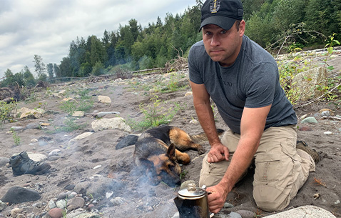 Master Sgt. Earl Plumlee makes coffee from a river with his dog Pepper. (Photo Courtesy of Plumlee Family)