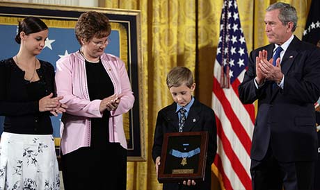 David Smith, 11-year-old son of Sgt. 1st Class Paul Smith, holds his fathers Medal of Honor, awarded Monday, April 4, 2005, posthumously by President Bush during ceremonies at the White House. Looking on are Smiths wife, Birgit, and step-daughter Jessica. Photo by Paul Morse.