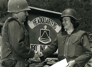 A female Soldier shakes the hand of a male soldier in Korea