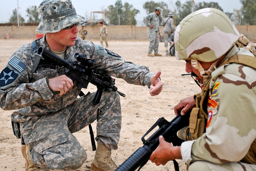 United States Soldier shows Iraq soldier how to lock his bolt to the rear when loading a magazine