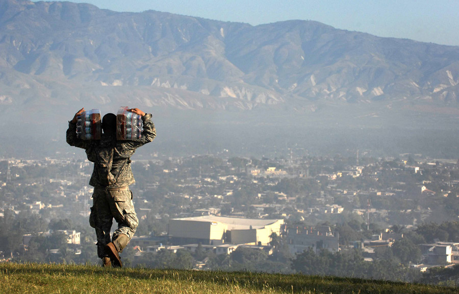 Soldier carries cases of water to Haiti earthquake victims in Port-au-Prince