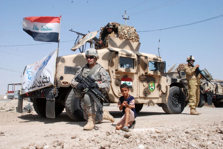 Soldier poses with boy in front of Humvee