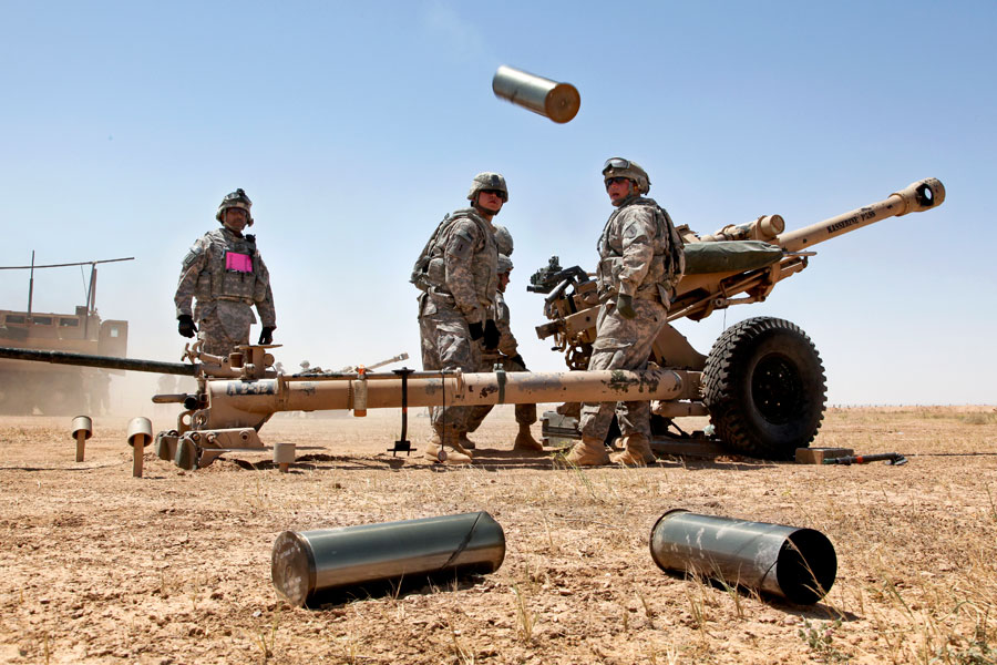 Soldiers stands ready to dispose of spent Howitzer brass during artillery training