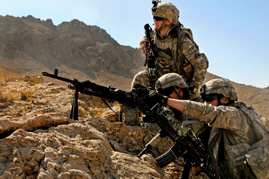 Soldiers peering through scope of rifle