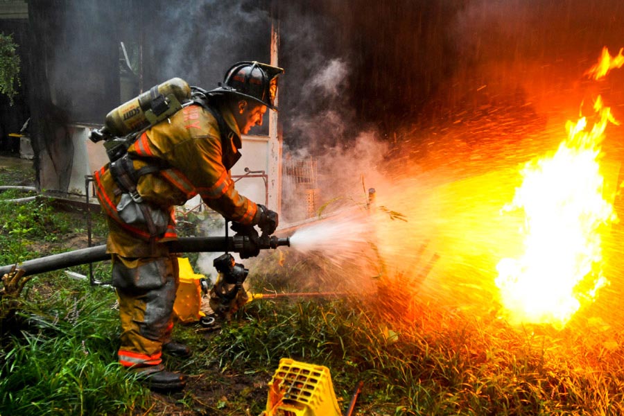 Private First Class Lucas Ternell, a volunteer firefighter, puts out a small debris fire in the yard of a house fire in Salisbury, Maryland