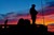 Soldier standing on Styker armored fighting vehicle at sunset