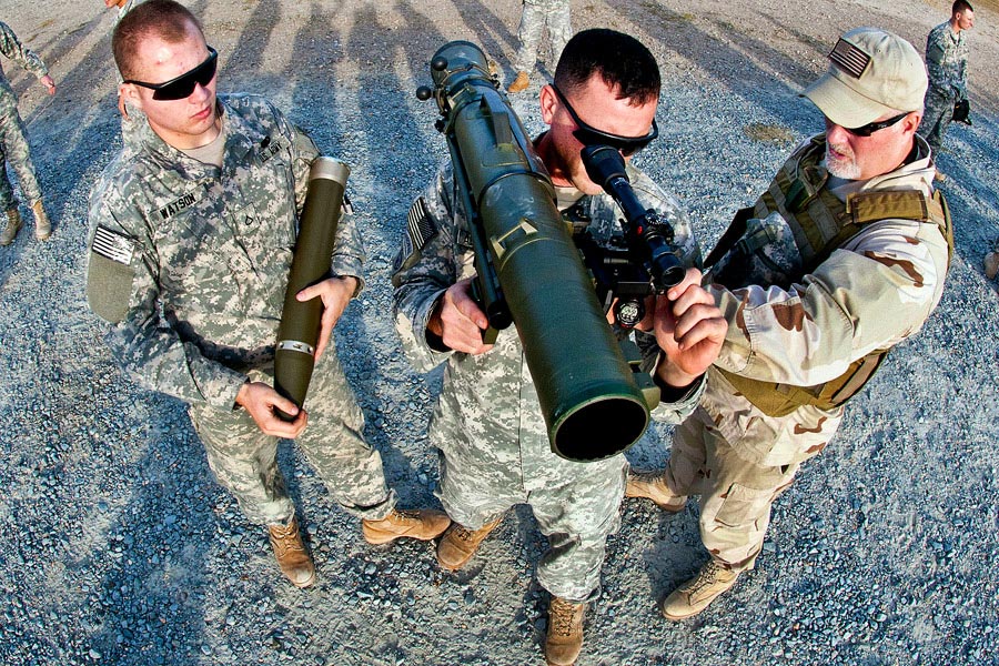 A civilian instructor coaches two paratroopers how to use a Carl Gustav 84 millimeter recoilless rifle