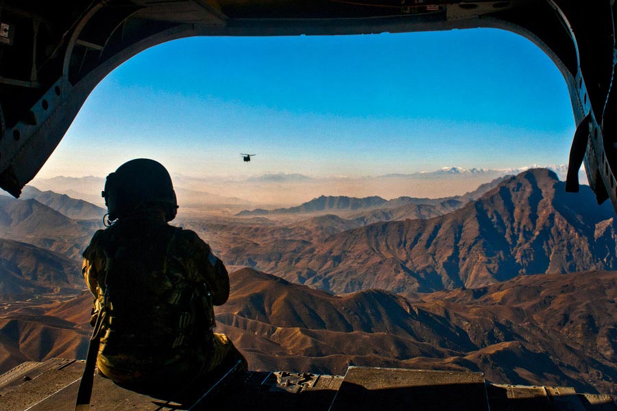 Specialist Devon Boxa looks out the back door of a CH-47D Chinook helicopter as another Chinook follows