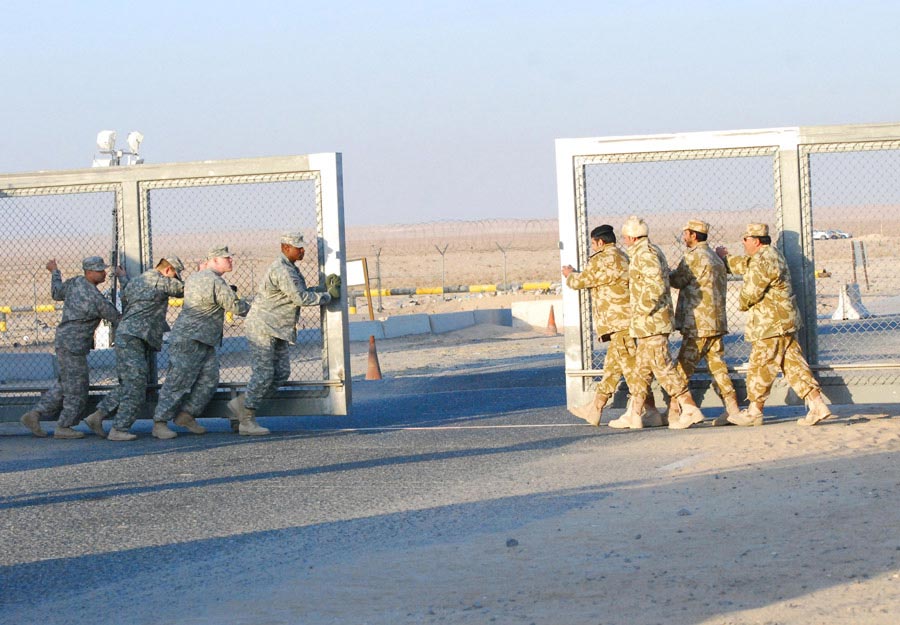 Kuwait border military police and Soldiers from the 265th Movement Control Team close the gate at the Khabari Crossing