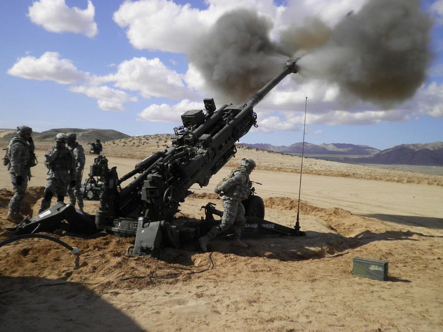 Soldiers firing a 155mm howitzer cannon