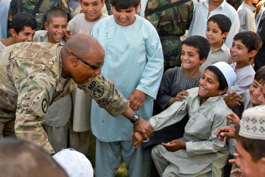 Captain Derrick W. Dew plays with young residents of Kandahar City during a ribbon cutting ceremony for a new soccer field