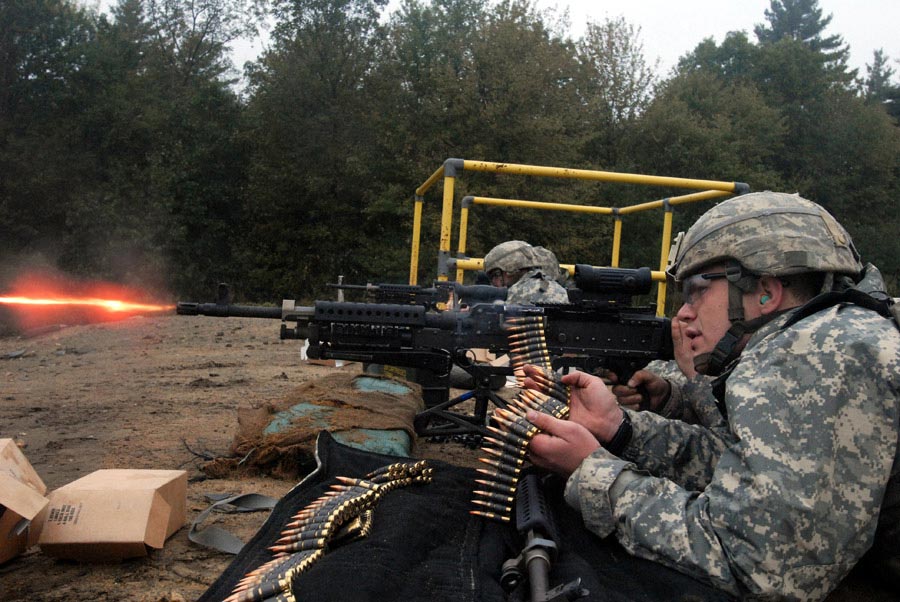 Private Stephen Justice acts as an assistant gunner and feeds rounds through a M240B machine gun