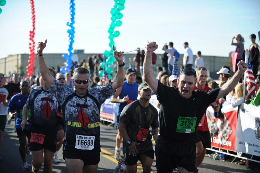 Major General David L. Mann (right) holds the hand of Captain Ivan Castro, a blind runner, while they approach the finish line at the 2011 Army Ten-Miler