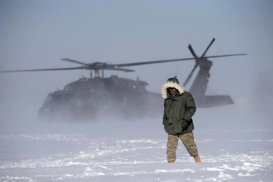 A Soldier oversees the liftoff of a UH-60 Black Hawk flown during medical evacuation training in harsh weather conditions