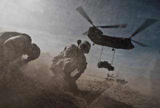 Staff Sergeant Hector Hoyas and Senior Airman Matthew Phillips turn away from the CH-47 Chinook helicopter prop wash