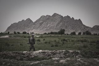 A Soldier walks through a valley during a patrol through Malajat, Afghanistan