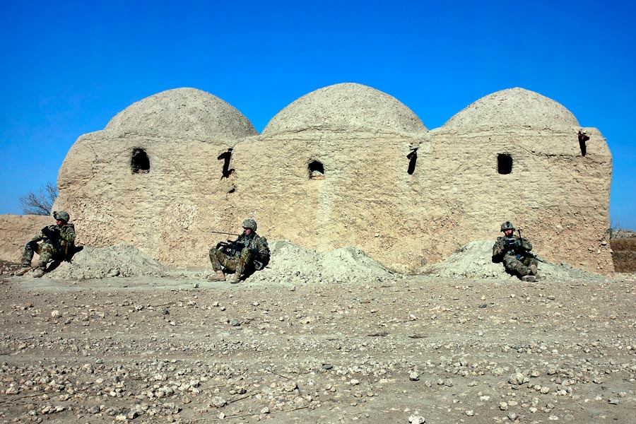 Soldiers from 504th Battlefield Surveillance Brigade, lean against mud wall