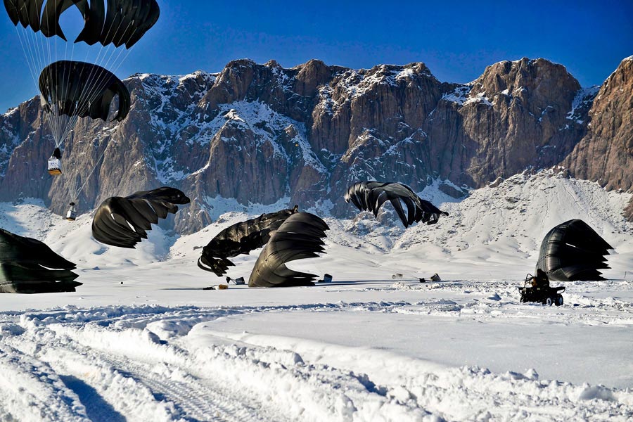 Pallets of supplies land in snow-covered ground during an airdrop in Afghanistan