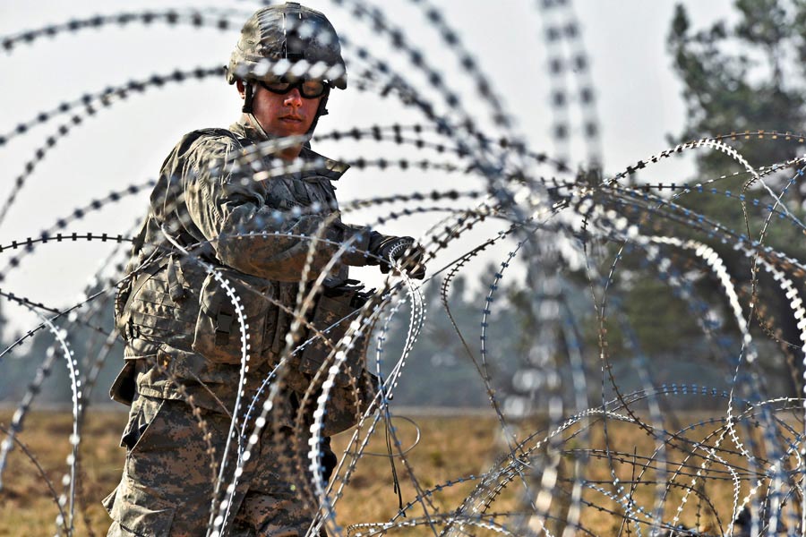 Private Vincent Redondo, I Company, lays out barbed wire during a Situational Training Exercise