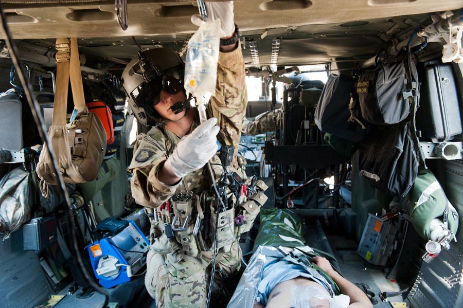 Specialist Thomas Appelhanz, flight medic with 101st Combat Aviation Brigade, checks on IV fluid of wounded Afghan National Army Soldier during patient transfer mission