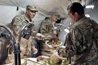 Captain Jefferson Mason, left, serves Thanksgiving dinner to a Soldier on Joint Combat Outpost Mushan, Afghanistan