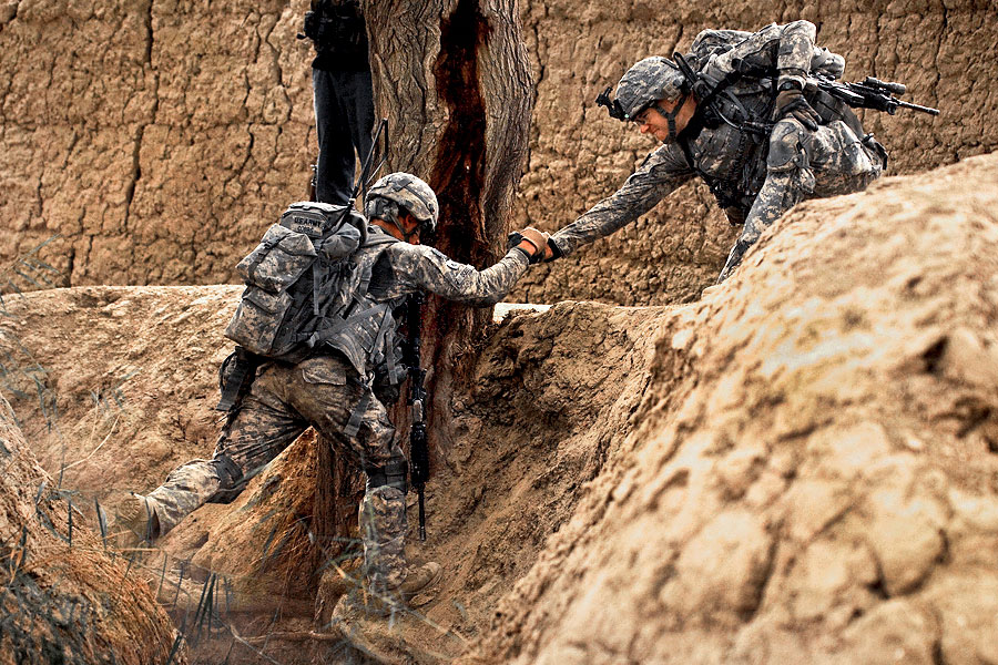 Camouflaged Soldiers cross ravine