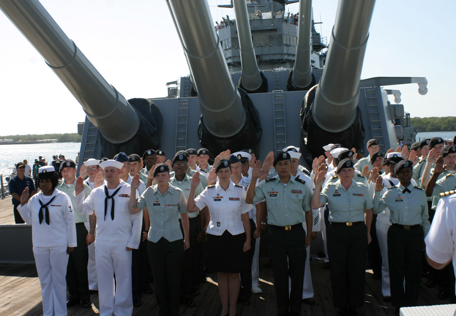 Soldiers, Sailors, Airmen and Marines raise their right hands as they recite the oath of enlistment on the EX-USS Missouri