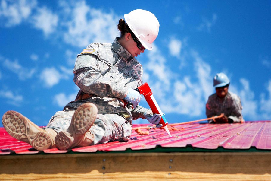 Private First Class Danielle Robinson seals gaps in sheet metal roofing during the Engineering Civic Action Program portion of Exercise Khaan Quest