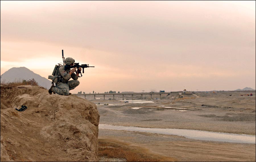 Specialist Nicholas Francioso kneels on cliff providing security for his squad