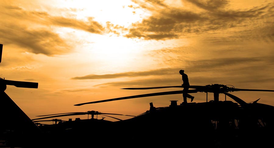 Chief Warrant Officer 2 Norma Garza, 1st Cavalry Division, conducts pre-flight inspection on UH-60 Black Hawk helicopter as sun rises